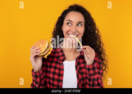 Excitée Lady Eating Delicious French Fries and Burger Banque D'Images