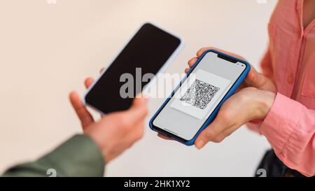 Homme utilisant le téléphone scannant le code QR sur le téléphone cellulaire intérieur, court Banque D'Images