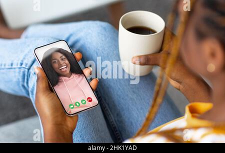 Femme noire tenant un téléphone portable dans la main appel vidéo à distance ami Banque D'Images