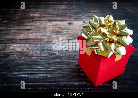 Boîte cadeau rouge sur table rustique en bois avec espace pour les copies, idéale pour Noël, la Saint-Valentin, les occasions spéciales Banque D'Images