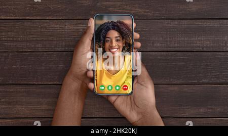 Femme noire tenant un téléphone portable dans la main appel vidéo à distance ami Banque D'Images