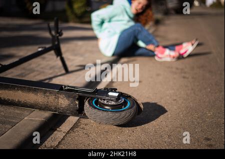 La femme caucasienne est tombée d'un scooter électrique et souffre de douleurs. Banque D'Images