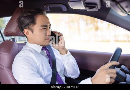 Jeune homme d'affaires parlant sur le téléphone et conduisant dans la voiture Banque D'Images
