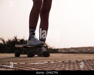 Skater femme jambes sur une planche à roulettes de surf Banque D'Images