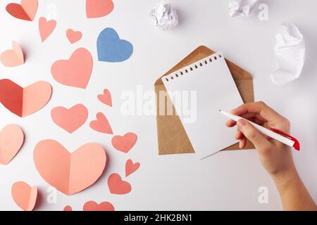 Saint-Valentin, une note avec une enveloppe et un stylo entre un grand nombre de coeurs en papier.Vue de dessus.Copier l'espace.Placer pour le texte. Banque D'Images