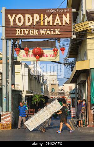 À la promenade de la rivière Yodpiman, Pak Klong Talat (marché), Bangkok, Thaïlande, un porteur pousse son chariot chargé de caisses Banque D'Images