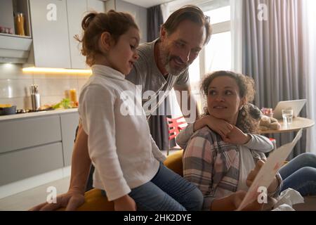 Fille et ses parents étudiant la peinture dans la cuisine Banque D'Images