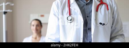 Le médecin tient la planchette à pince avec les documents médicaux en arrière-plan le patient est assis Banque D'Images