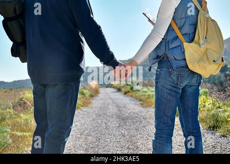 Couple aimant tenant les mains tout en marchant en milieu rural.Femme à la recherche d'un gps pour utiliser la carte dans son smartphone.Concept d'amitié et de relation.Puits B Banque D'Images