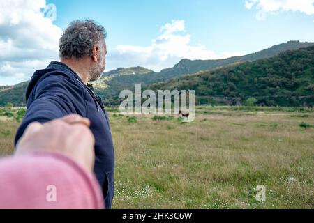 Suivez-moi.L'homme tient et tire la main du photographe tout en marchant sur le pâturage et la mène vers les chevaux.Concept d'Union et nouveau moderne Banque D'Images