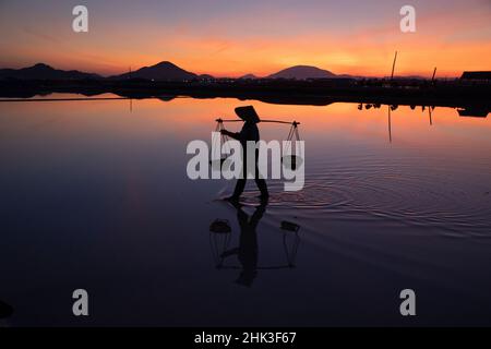 Vietnam.Doc Laissez Salt Lake.Les travailleurs récoltant le sel.Lever du soleil tôt le matin. Banque D'Images