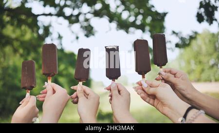 Les amies tiennent la glace au chocolat sur un bâton de suite. Banque D'Images