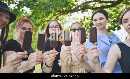 Les amies tiennent la glace au chocolat sur un bâton de suite. Banque D'Images