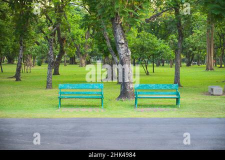 Deux bancs verts en dessous sur les arbres dans le parc pour permettre aux gens de se détendre lorsqu'ils voyagent, de l'exercice et d'autres sur le parc public Banque D'Images