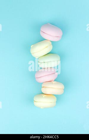 Le guimauve empilé multicolore ressemble à des macarons français sur fond bleu Banque D'Images