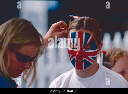 Femme qui dépique le visage d'une autre femme avec le drapeau britannique, 1990s Banque D'Images