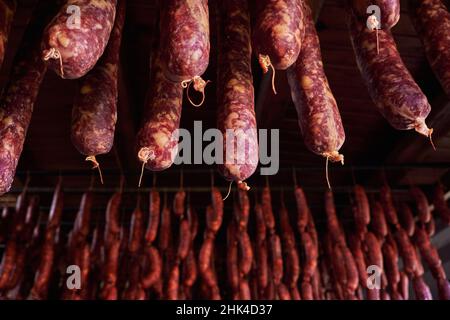 Soucoupes maison traditionnelles et chorizos espagnols suspendus à sécher dans la salle de cure Banque D'Images