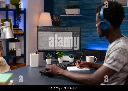 Architecte technique afro-américain analysant des plans immobiliers concevant des prototypes de bâtiment travaillant à distance de la maison.Entrepreneur jeune adulte développant un produit architectural Banque D'Images