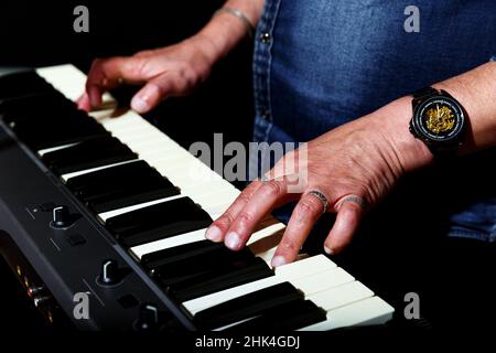 homme âgé en chemise bleue en denim joue les clés sur scène sur fond noir. main gros plan Banque D'Images
