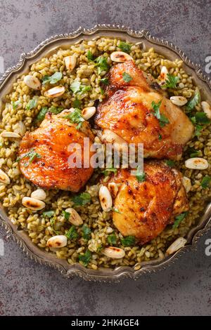 Le Freekeh au poulet est un délicieux repas préparé avec le grain et servi avec des noix grillées et des herbes dans l'assiette sur la table.Vertical haut vi Banque D'Images