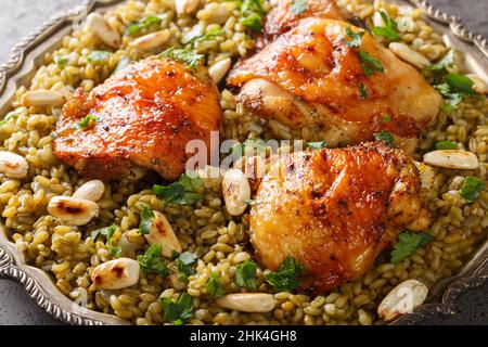 Poulet libanais servi sur un lit de blé vert séché au feu avec une garniture de noix grillées sur la table.Horizontale Banque D'Images