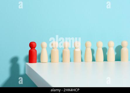 figurines en bois d'hommes et une rouge sur fond bleu.Concept de responsable et de recrutement.Personnalité toxique dans l'équipe Banque D'Images