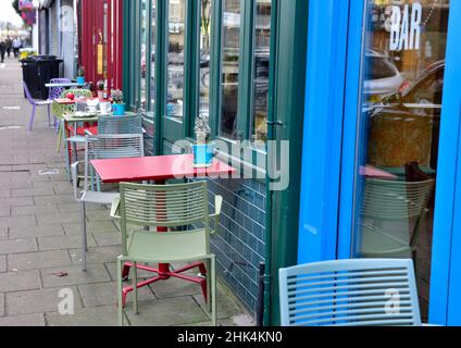 Rangée de tables et de chaises vides colorées sur le trottoir à l'extérieur du bar café attendant les clients Banque D'Images