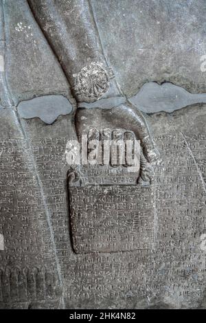 Relief antique représentant un seau d'eau sainte, porté par un génie ailé avec l'écriture cuneiform.Civilisation assyrienne et sumérienne (883-859 BCE). Banque D'Images