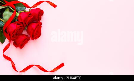 Roses rouges sur fond rose.Confession d'amour.Célébration de la Saint-Valentin.Roses rouges et ruban, concept de la Saint-Valentin, anniversaire, la da de mère Banque D'Images