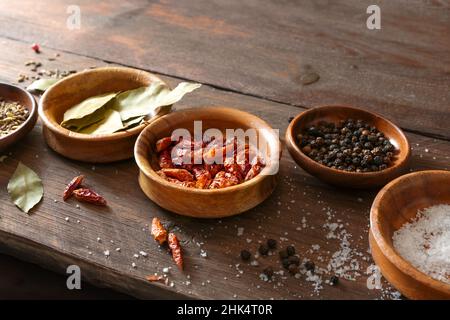 Épices dans de petits bols comme les feuilles de Laurier, sel, poivre et piment sur une table rustique en bois, espace de copie, foyer sélectionné, profondeur de champ étroite Banque D'Images