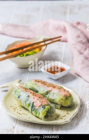 Deux petits pains d'été avec salade et saumon et sauce sur fond de bois blanc, cuisine japonaise, asiatique, verticale Banque D'Images