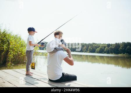 Un père avec deux jeunes fils pêche sur le lac en été le week-end Banque D'Images