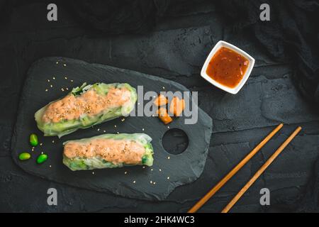Deux petits pains d'été avec salade et saumon sur fond noir, cuisine japonaise et asiatique, vue de dessus Banque D'Images