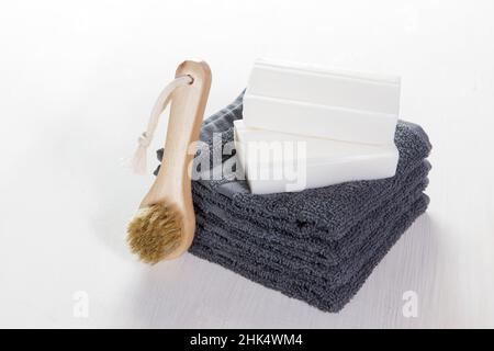 Ensemble spa de serviettes grises, savon et brosse en bois avec des poils naturels pour le visage sur fond de bois blanc.Coffret cadeau, vue latérale, orientation horizontale Banque D'Images