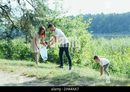 le volontaire familial nettoie les ordures dans la nature.Père et mère, parents, enfants, fils famille bénévoles dans une journée ensoleillée nettoyer les déchets de déchets de baise bo Banque D'Images