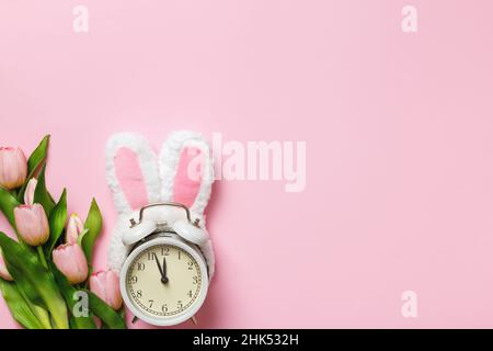 Carte de Pâques.Réveil avec des oreilles de lapin fleurs tulipes sur fond rose.Vue de dessus de l'espace de copie de la mise à plat Banque D'Images
