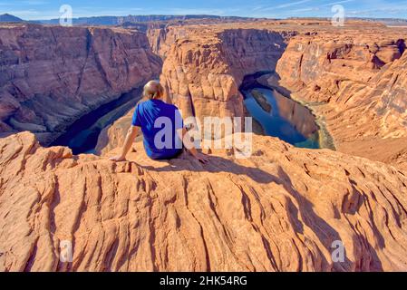 Un homme assis au bord d'une falaise surplombant Horseshoe Bend près de page, Arizona, États-Unis d'Amérique, Amérique du Nord Banque D'Images