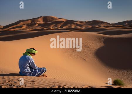 Un berbère en robe traditionnelle se trouve parmi les dunes de sable d'Erg Chebbi, Sahara Desert, Maroc, Afrique du Nord, Afrique Banque D'Images