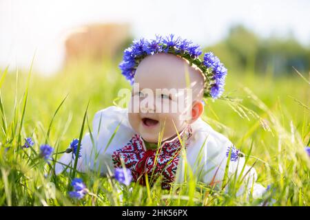 Une petite fille heureuse en vêtements biélorusses ou ukrainiens se trouve sur l'herbe et rit.Magnifique enfant slaves.Un petit bébé dans un brodé Banque D'Images