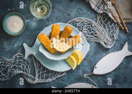 Doigts de poisson avec décoration citron et marine sur fond bleu, vue de dessus Banque D'Images