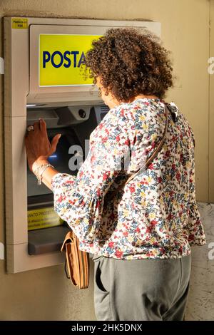 29 août 2021, Vicenza, Italie: Femme d'âge moyen qui retire de l'argent de sa carte de crédit à l'ATM de la poste italienne Banque D'Images
