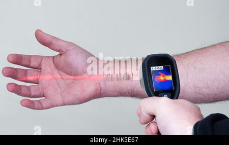 le scanner lit un code-barres sur le bras d'un homme. lecteur optique infrarouge. rayons rouges et thermographe montrant le bras sur l'écran Banque D'Images
