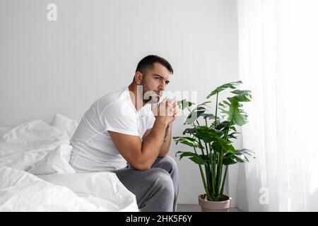 Pensif triste fatigué millénaire musculaire européen homme assis sur le lit souffrant seulement de dépression et de stress Banque D'Images