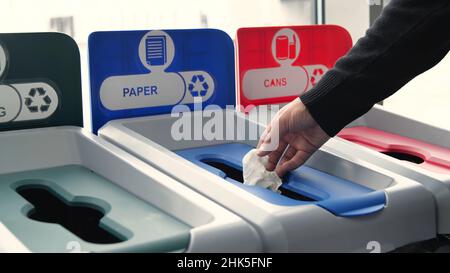 Gros plan d'un homme qui jette des ordures dans les bacs de tri.Médias.L'homme jette les ordures dans des bacs de couleur pour le tri.Le tri des déchets aide au recyclage et au su Banque D'Images