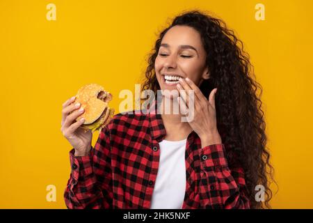 Happy Raughing Lady Eating Burger au Studio Banque D'Images