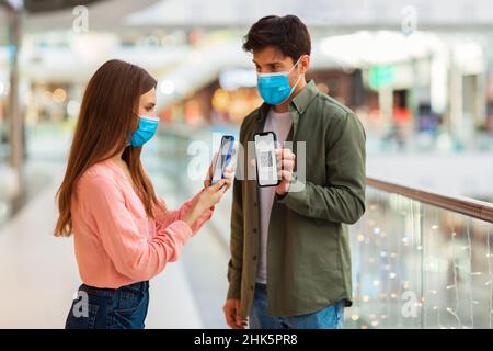 Couple montrant des téléphones avec des codes QR portant des masques dans Hypermarket Banque D'Images