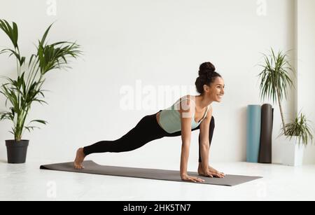 Jeune belle femme faisant de l'entraînement de yoga dans le studio moderne et spacieux Banque D'Images