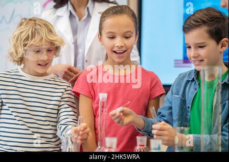 Enfants faisant l'expérience liquide en classe de chimie Banque D'Images