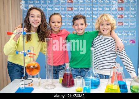 Les enfants s'embrassant devant un appareil photo en classe de chimie Banque D'Images