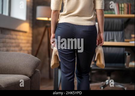 Dame avec des chaussures à talons hauts debout dans une pièce Banque D'Images